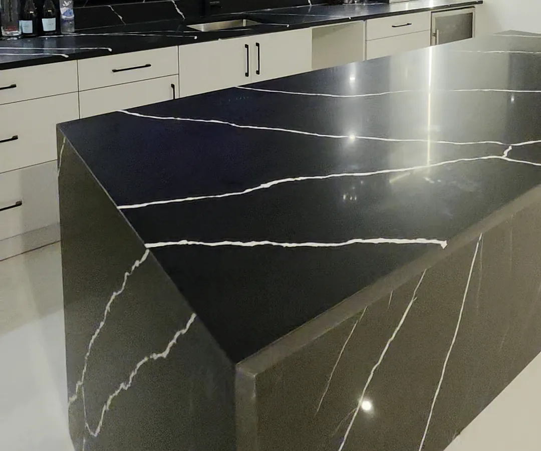 Mitred waterfall corner where the black stone top meets the side panel, with veining carried around the edge